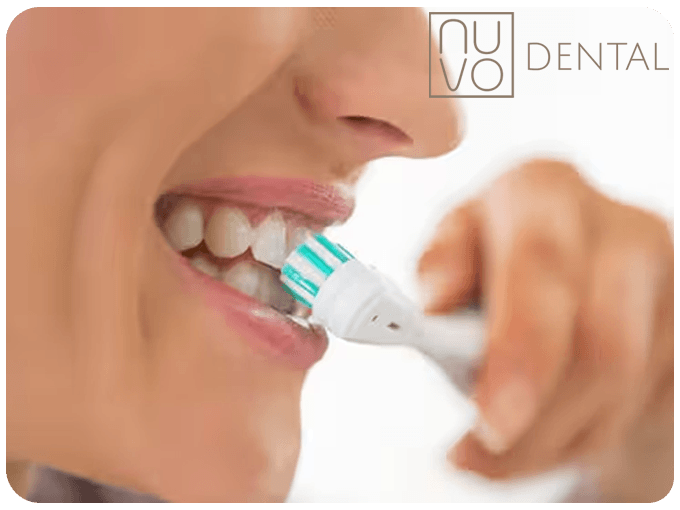 A woman brushing her teeth with a electric toothbrush